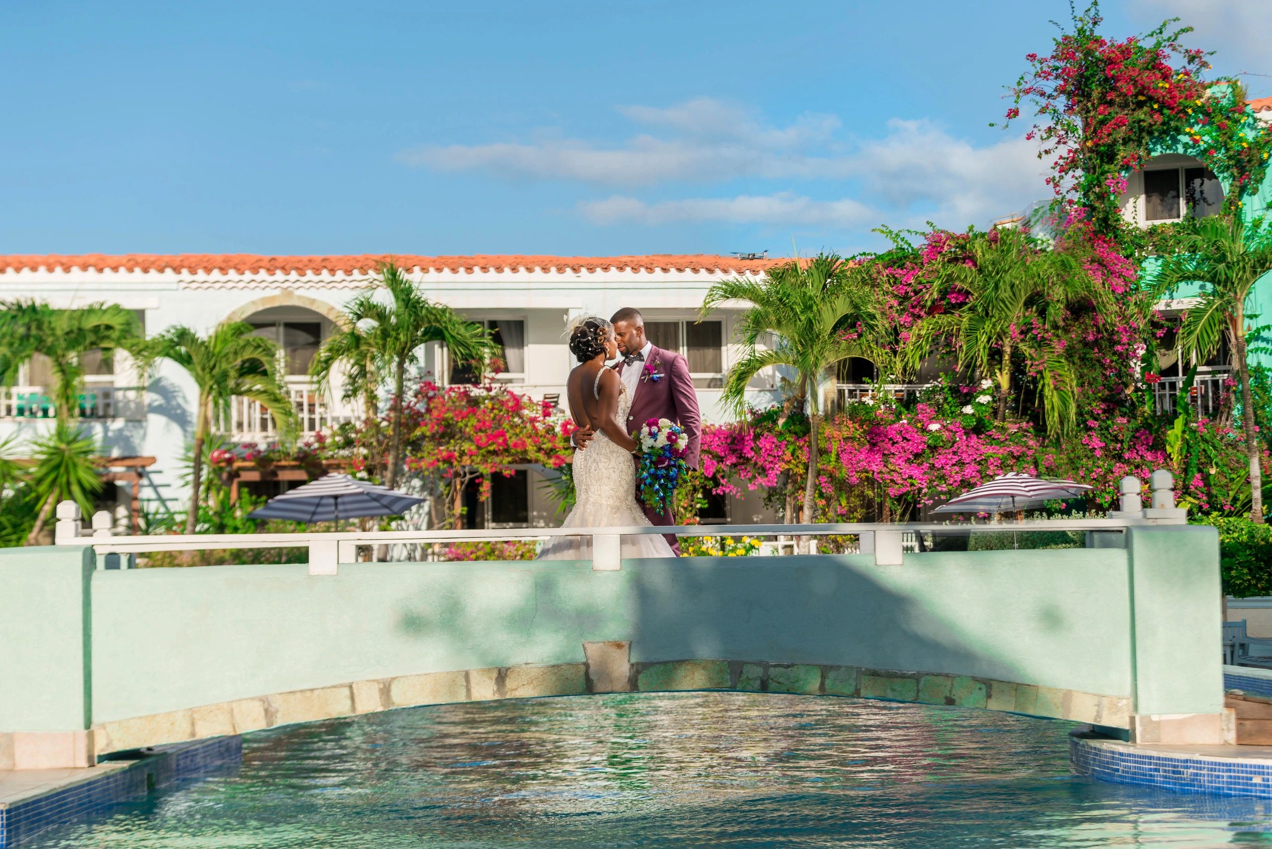 A bride and group on their wedding day in Antigua on a bridge with a backdrop of tropical flowers.