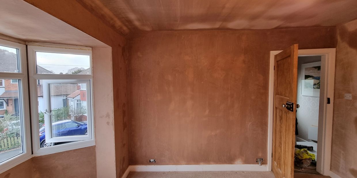 Empty room with freshly plastered walls and an open door.