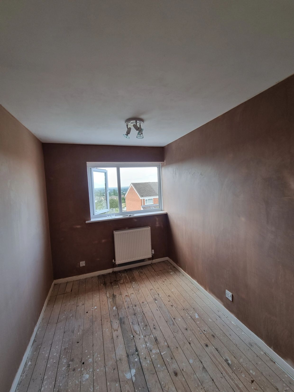 Empty room with freshly plastered walls and wooden floorboards.