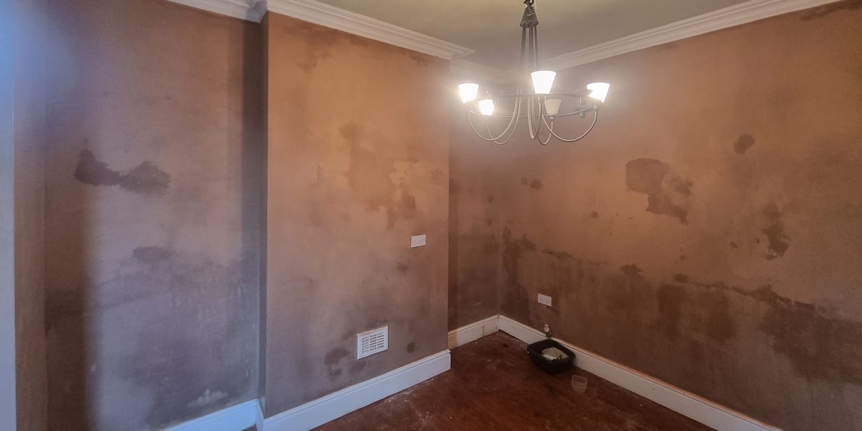 Room with unfinished plastered walls and a chandelier.