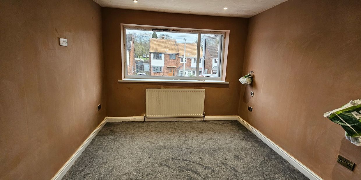 Empty room with freshly plastered walls and grey carpet.