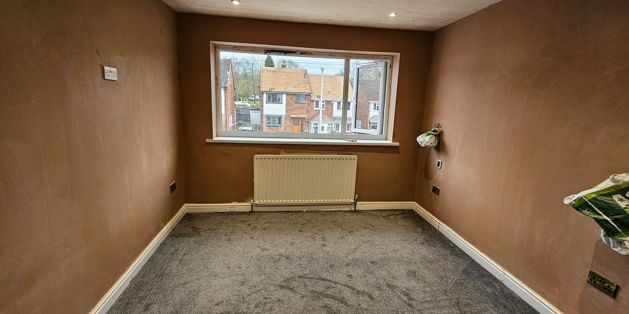 Empty room with freshly plastered walls and grey carpet.