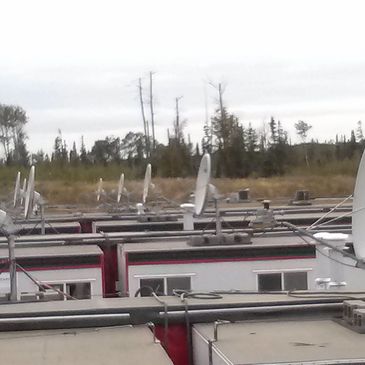 Rows of trailers with satellite dishes in a rural setting under an overcast sky.
