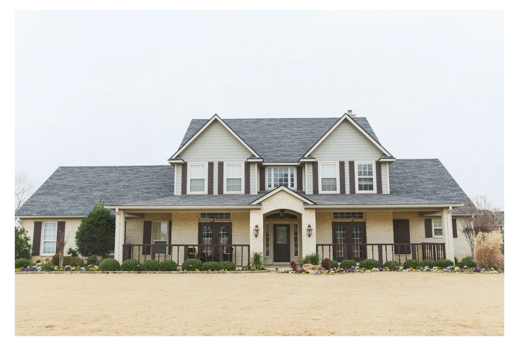 Large two-story house with a wide porch and manicured garden.