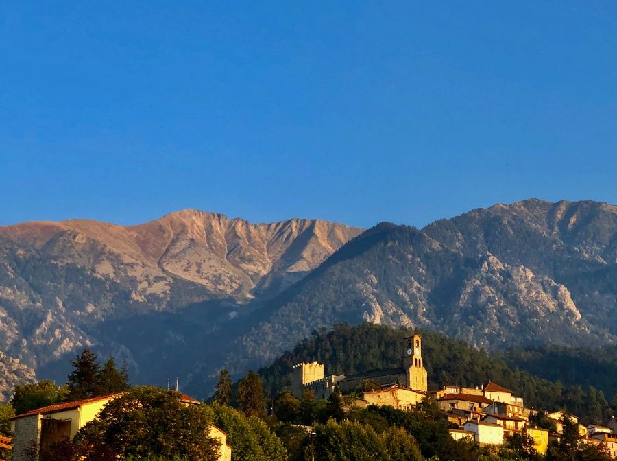 A brown, rocky Canigou as it stands against a blue sky and well above Vernet les Bains, France.