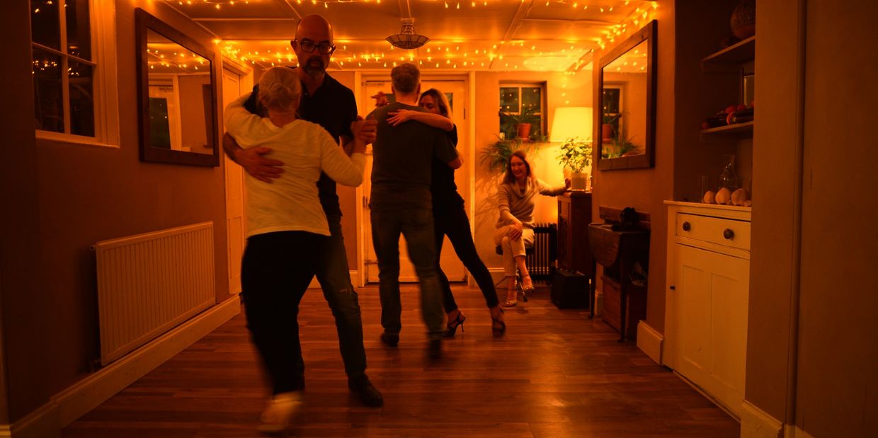 Couples enjoying a warm, intimate dance in a cozy room with string lights at tango lessons Colchester and Argentine tango workshops in tango classes Essex.