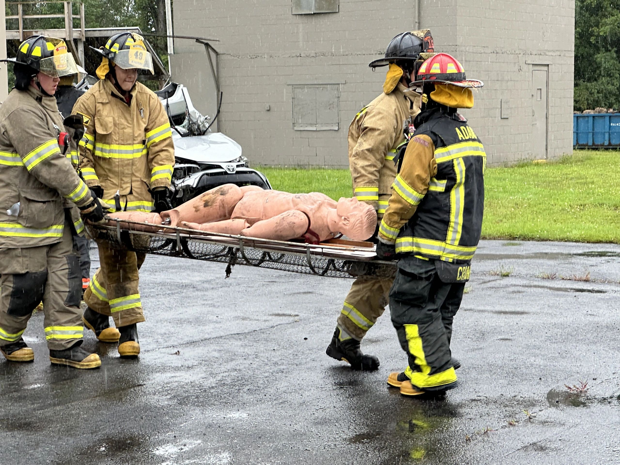 Firefighters carry a rescue training dummy on a stretcher.