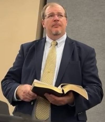 Man in suit holding an open book.
