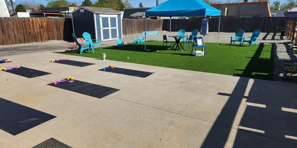 Outdoor yoga setup with mats and flower decorations under a blue canopy.