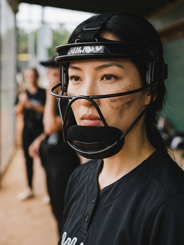 Female softball player with helmet and face paint focused during game.
