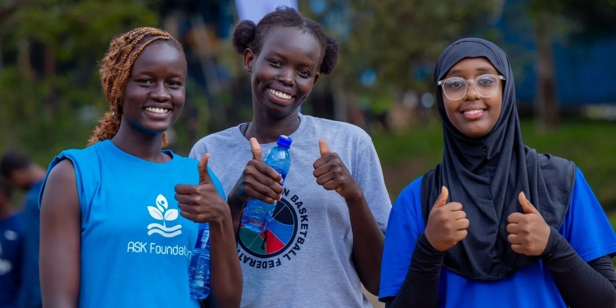 Three women giving thumbs up and smiling.