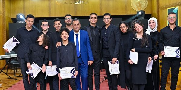 Group photo of young individuals holding certificates with a man in a blue suit.