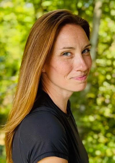 Portrait of a woman with long hair smiling outdoors.