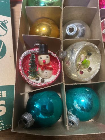A box of vintage Christmas ornaments, including a snowman and shiny balls.