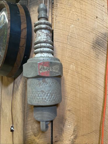 Old Champion spark plug mounted on wooden wall.