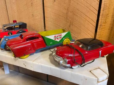 Three vintage toy cars on a plastic table.