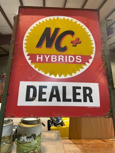 Vintage NC+ Hybrids dealer sign with rustic decor.