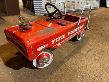 Vintage red children's firefighter pedal car toy.