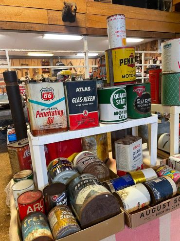 Collection of vintage oil cans and containers arranged on shelves.