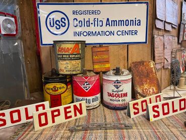 Vintage ammonia and oil cans with informational signs and sold/open placards.