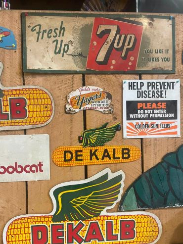 Vintage signs featuring 7 Up, DeKalb, and disease prevention.