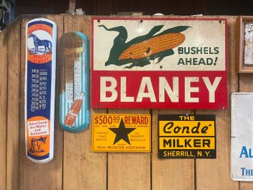 Vintage signs and thermometer on wooden wall.