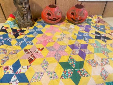 Colorful quilt with sculptures and pumpkin decorations.