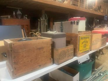 Old wooden crates and boxes lined up on a table in a barn or storage area.