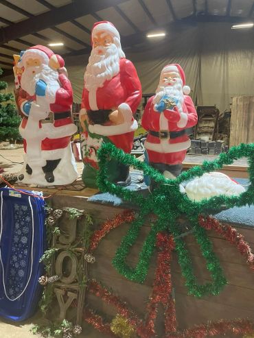 Three Santa Claus decorations behind a table with holiday decor.