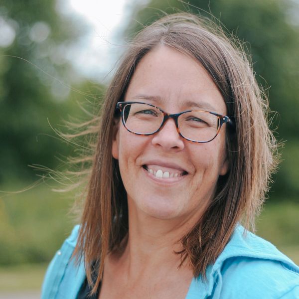 Jill L'Esperance, founder of Restore Peak Health, smiling outdoors with a warm and welcoming express