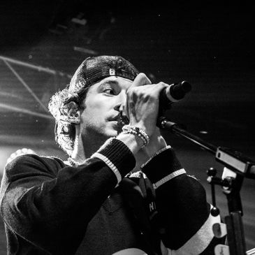 Black and white photo of a young male singer performing on stage with a microphone.