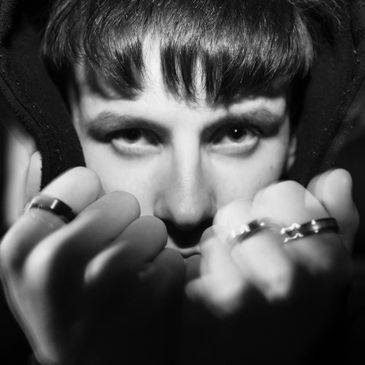 Close-up black and white portrait of a person with rings on their fingers.