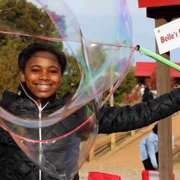 Girl smiling looking through giant bubbles. 