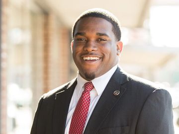 Headshot of a smiling man in a suit.
