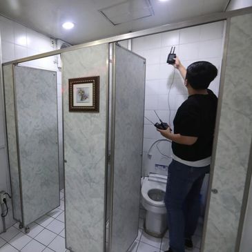 Man checking signals inside a bathroom stall.
