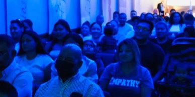 Público sentado en un evento con luz azul.