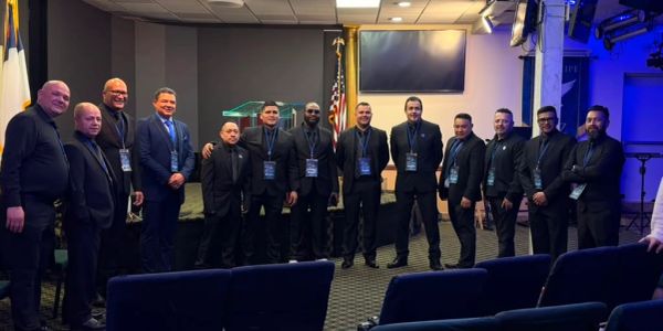 Grupo de hombres vestidos formalmente posando en interior.