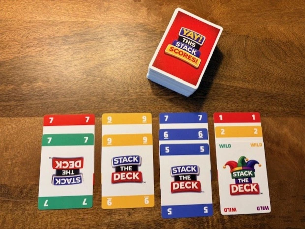 Stack the Deck card game with colorful numbered and wild cards on a wooden table.