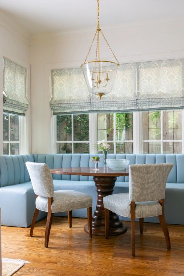 Elegant dining nook with blue bench and wooden table.