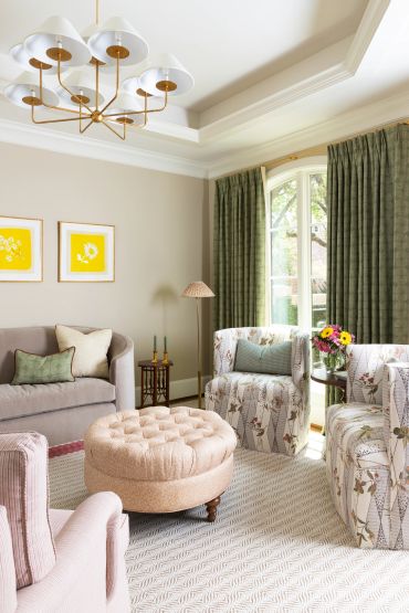 Cozy living room with floral chairs and a round ottoman.
