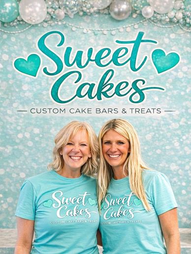 Two women smiling in matching Sweet Cakes t-shirts with a custom cake bar backdrop.