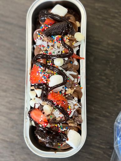 Colorful dessert with strawberries, chocolate, marshmallows, and sprinkles in a rectangular container.