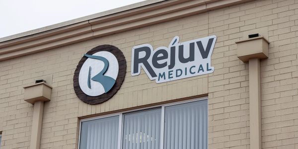 Sign for Rejuv Medical on a beige brick building.
