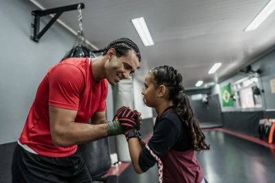 A coach encourages a young boxer in a gym.