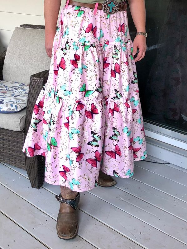 Person wearing a colorful butterfly-patterned skirt and brown boots.