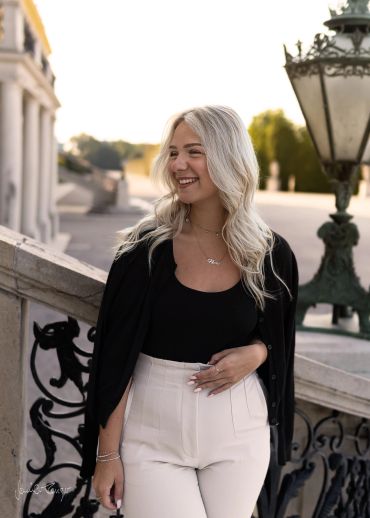 Frau mit blondem Haar lächelnd im Freien an einer historischen Treppe.