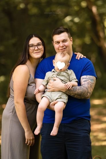 Familienfoto mit Eltern und Baby im Freien.