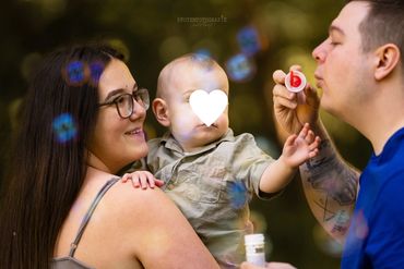 Familie spielt mit Seifenblasen im Freien.