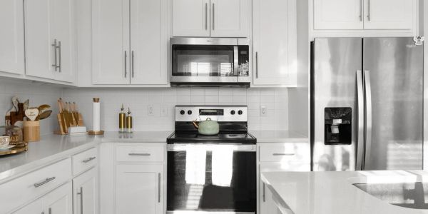Modern white kitchen with stainless steel appliances and clean countertops.