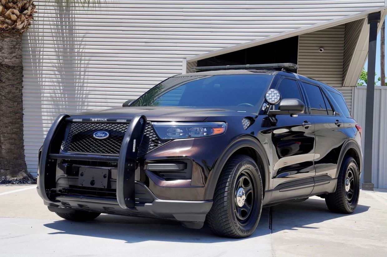 Black Ford police SUV with push bumper and spotlight parked outdoors.